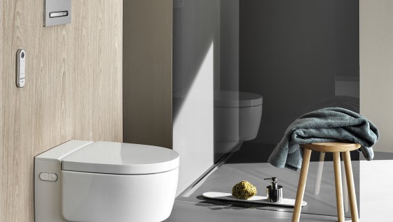 WC lavant Geberit AquaClean Maïra Comfort avec télécommande et plaque de déclenchement Sigma50 (© Geberit) WC lavant Geberit AquaClean Maïra Comfort avec télécommande et plaque de déclenchement Sigma50 (© Geberit)