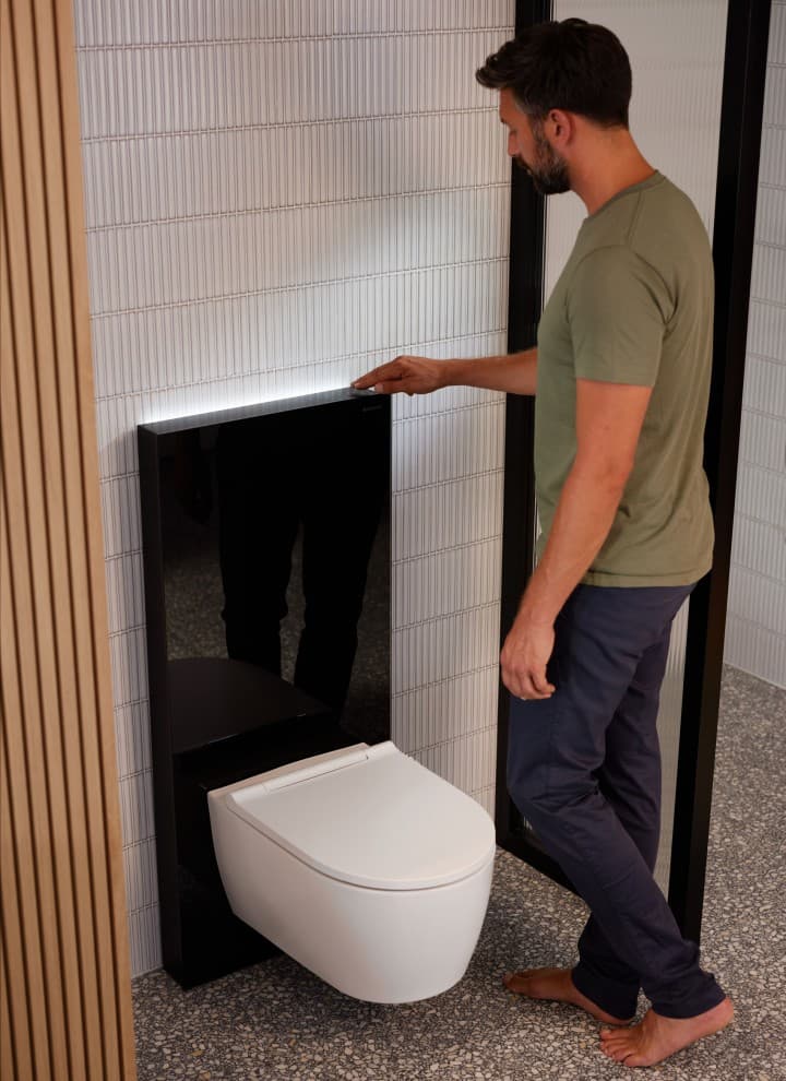 Un homme à côté d'un Geberit Monolith Plus avec ComfortLight Un homme à côté d'un Geberit Monolith Plus avec ComfortLight