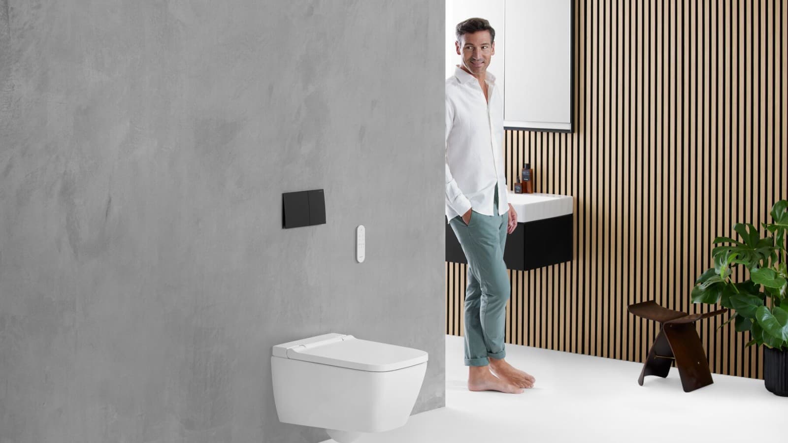 Homme dans une salle de bain avec le WC lavant Geberit AquaClean Sela Square Homme dans une salle de bain avec le WC lavant Geberit AquaClean Sela Square