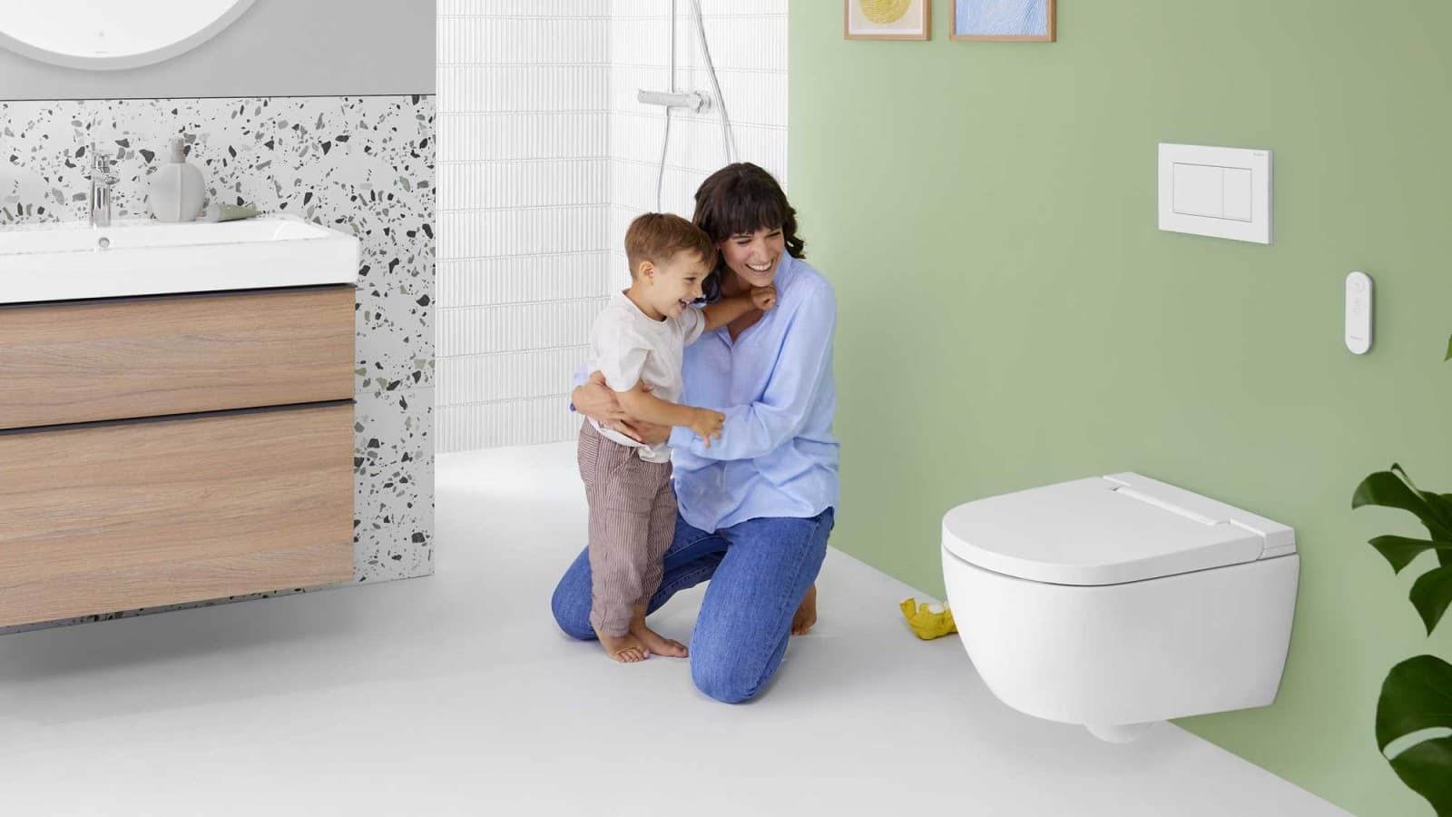 Femme avec enfant devant un WC lavant Geberit AquaClean Alba Femme avec enfant devant un WC lavant Geberit AquaClean Alba
