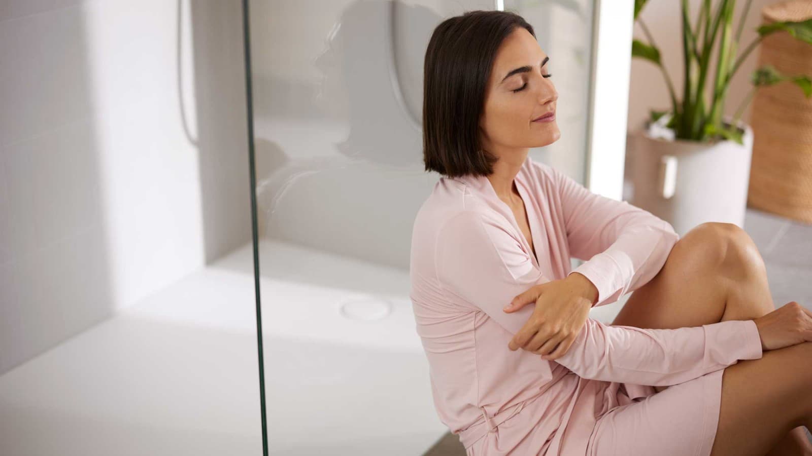 Femme assise dans la salle de bain devant la douche Femme assise dans la salle de bain devant la douche