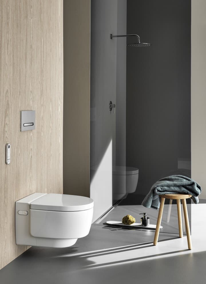 WC lavant Geberit AquaClean Maïra Comfort avec télécommande et plaque de déclenchement Sigma50 (© Geberit) WC lavant Geberit AquaClean Maïra Comfort avec télécommande et plaque de déclenchement Sigma50 (© Geberit)